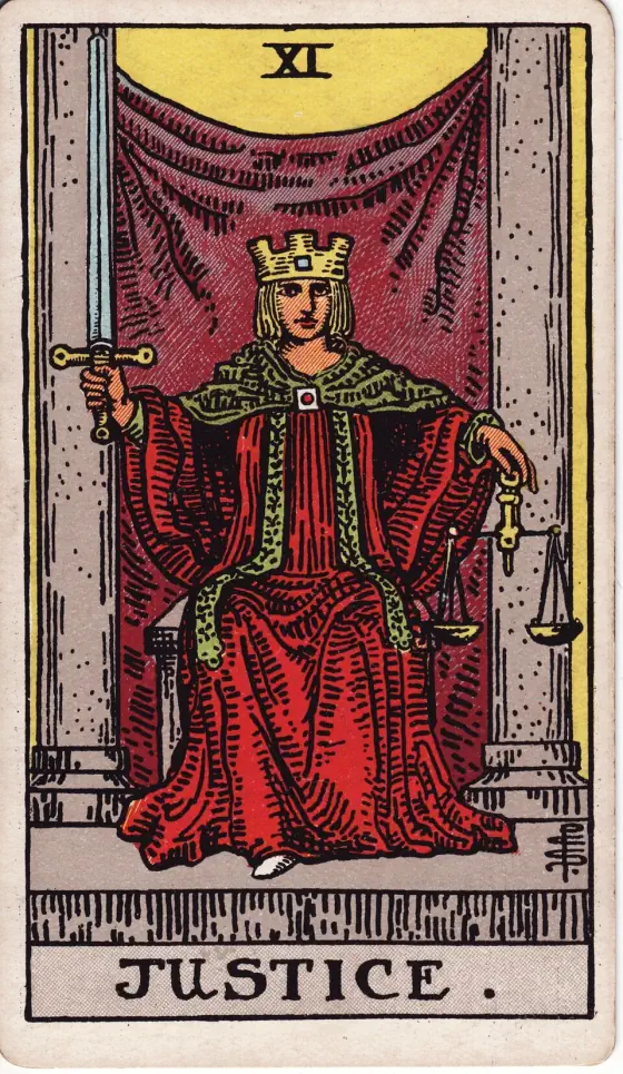 Justice: A crowned figure in a red robe sits between two stone pillars in front of a purple veil, holding an upright sword in the right hand and a pair of scales in the left.
