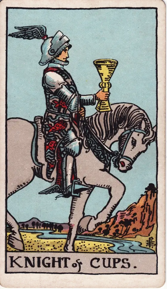 Knight of Cups: A knight in a winged helmet rides a grey horse at a walk, holding out a cup, near a river winding between hills.
