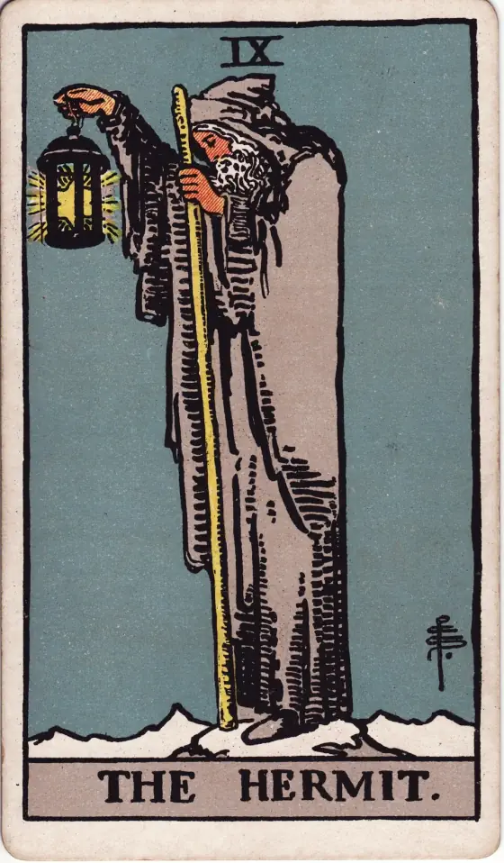 The Hermit: An old bearded man in a grey hooded cloak stands on a snowy peak, holding up a lantern with a star inside it and leaning on a tall staff.