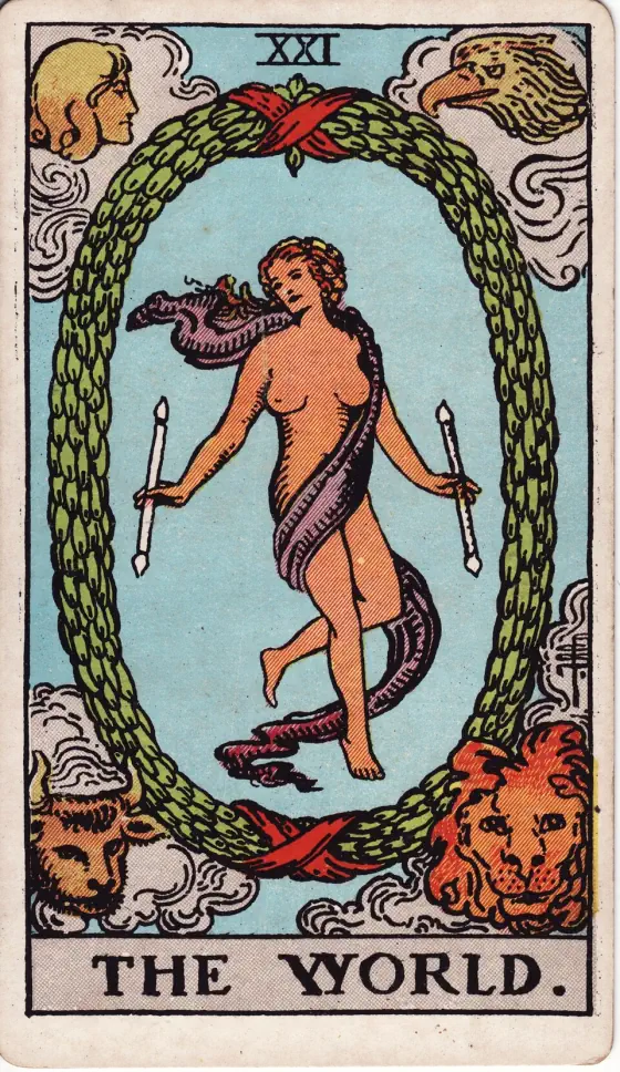 The World: A woman wrapped in a long scarf dances inside an oval wreath with a wand in each hand, while a man's head, an eagle, a bull and a lion look on from the four corners.
